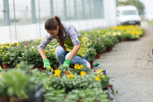 Gardener with tools and safety gear at a property entrance